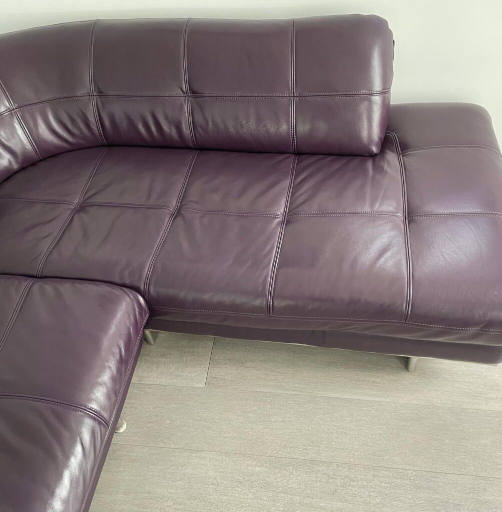 Plum-coloured leather corner sofa professionally restored with repaired upholstery and a smooth, colour-matched finish.