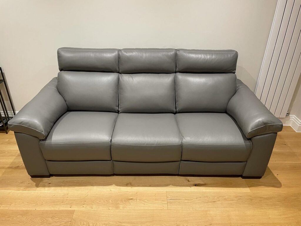 Three-seater grey leather sofa professionally restored with repaired cushions and refreshed leather upholstery.