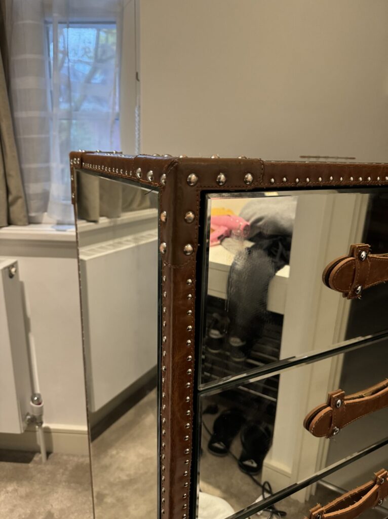 Mirrored chest of drawers with leather-look trim and stud detailing after professional repair and restoration.