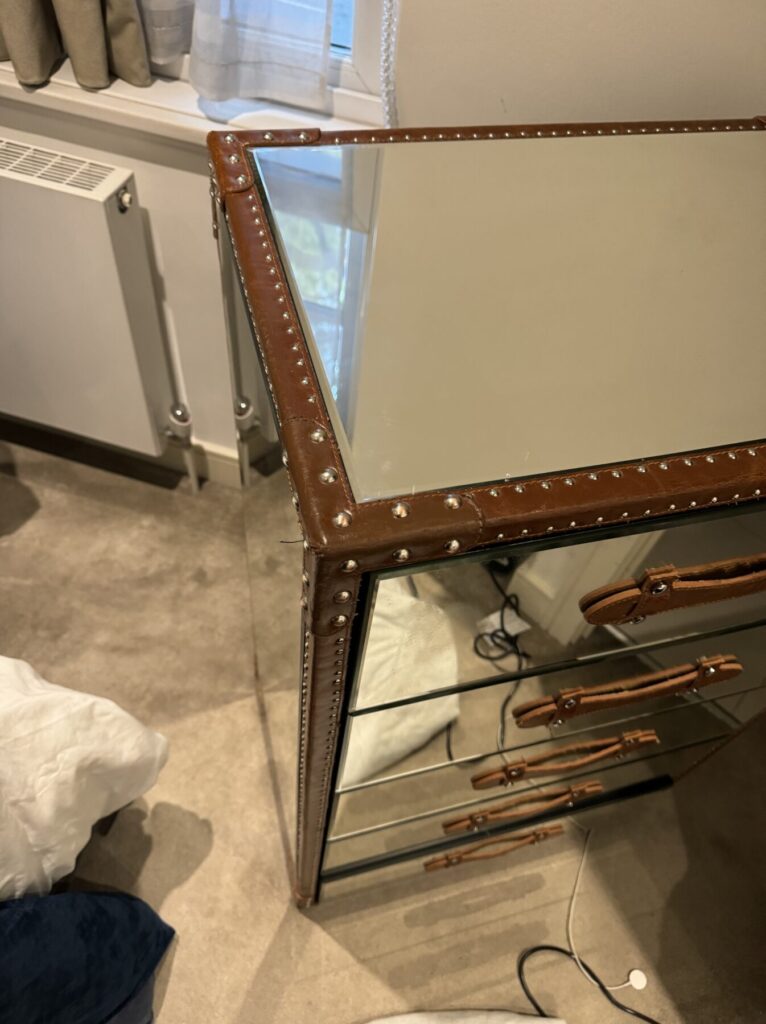 Mirrored chest of drawers with leather-look trim and stud detailing, restored to a clean and polished finish.