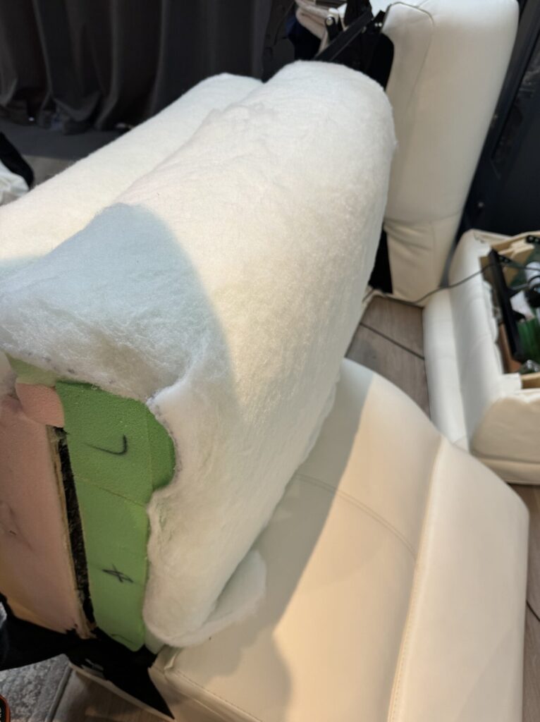 White leather recliner cushion being rebuilt with new foam and padding during professional furniture restoration.