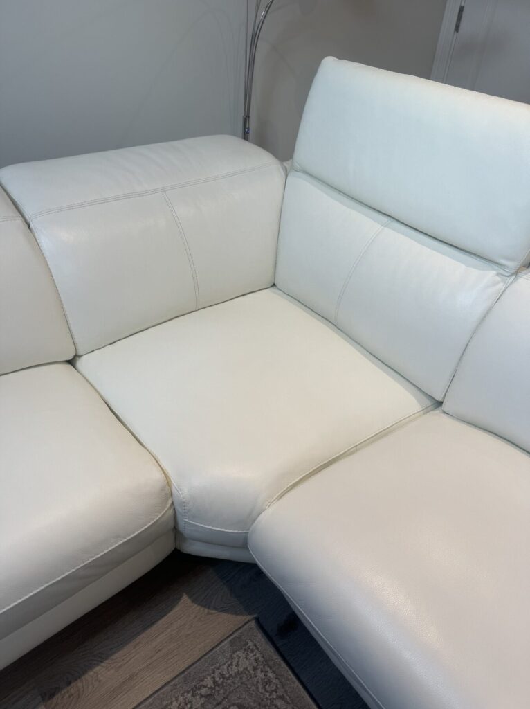 Close-up of a white leather corner sofa showing professional leather repair and restoration to the seating area.