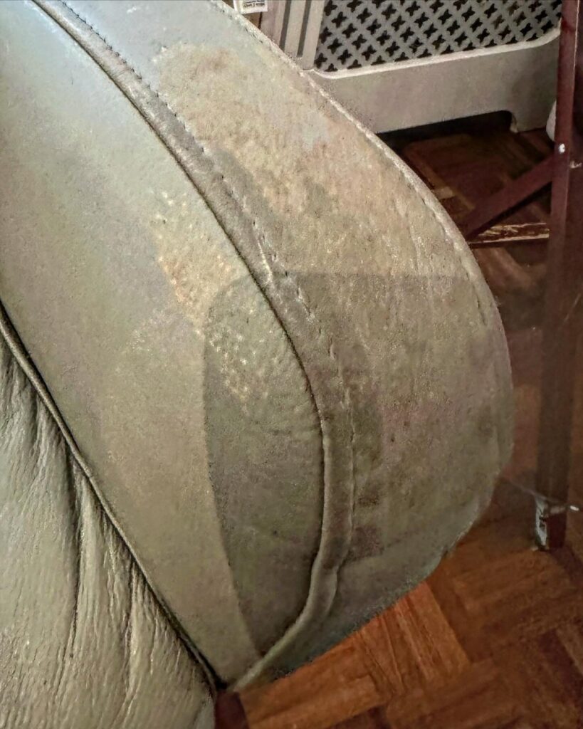 Beige leather recliner armrest showing heavy wear, discolouration, and surface damage prior to restoration.