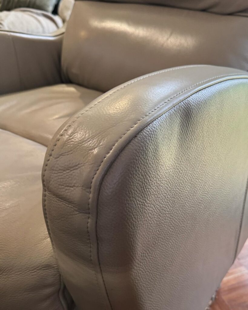Light grey fabric sofa cushion showing multiple stains and marks prior to professional upholstery cleaning.