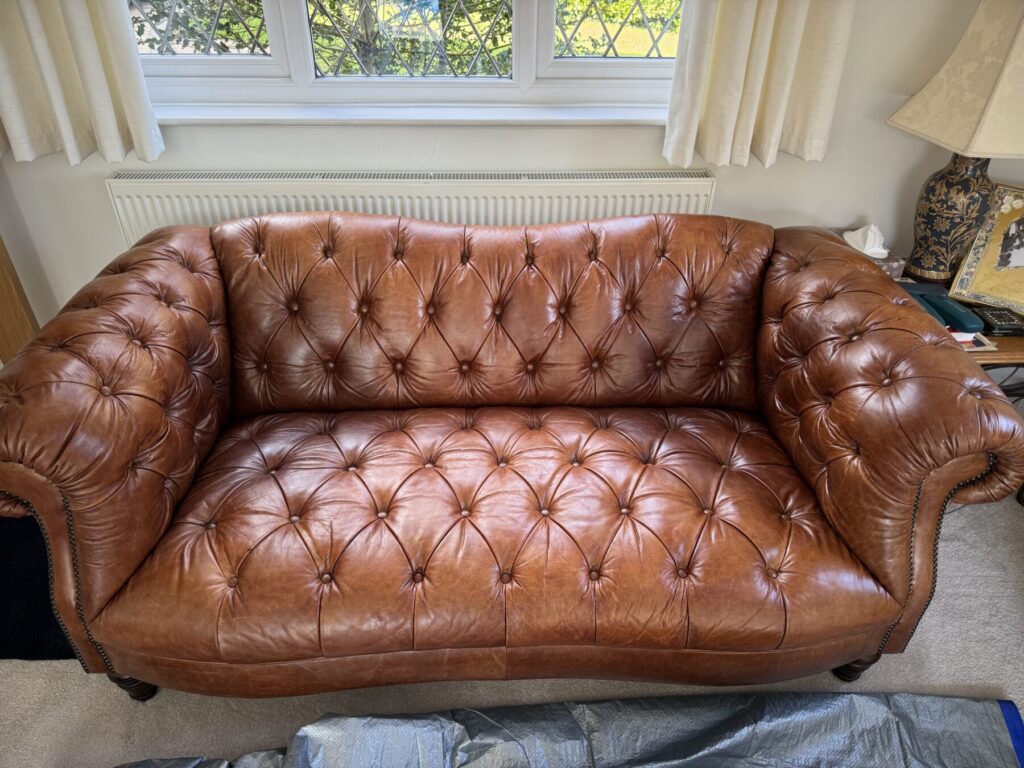 Brown Chesterfield-style leather sofa with deep button detailing and restored leather upholstery.