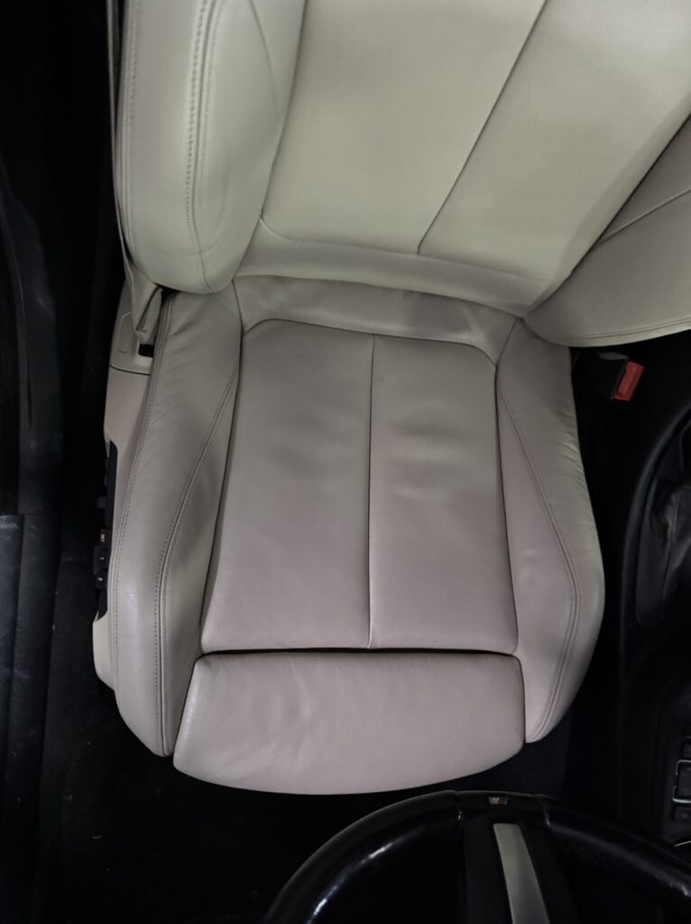 Cream leather car seat cushion showing restored upholstery with smooth panels and improved finish.