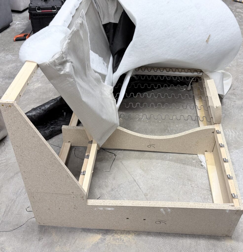 Dismantled sofa frame exposing springs and internal structure during furniture repair and reupholstery.