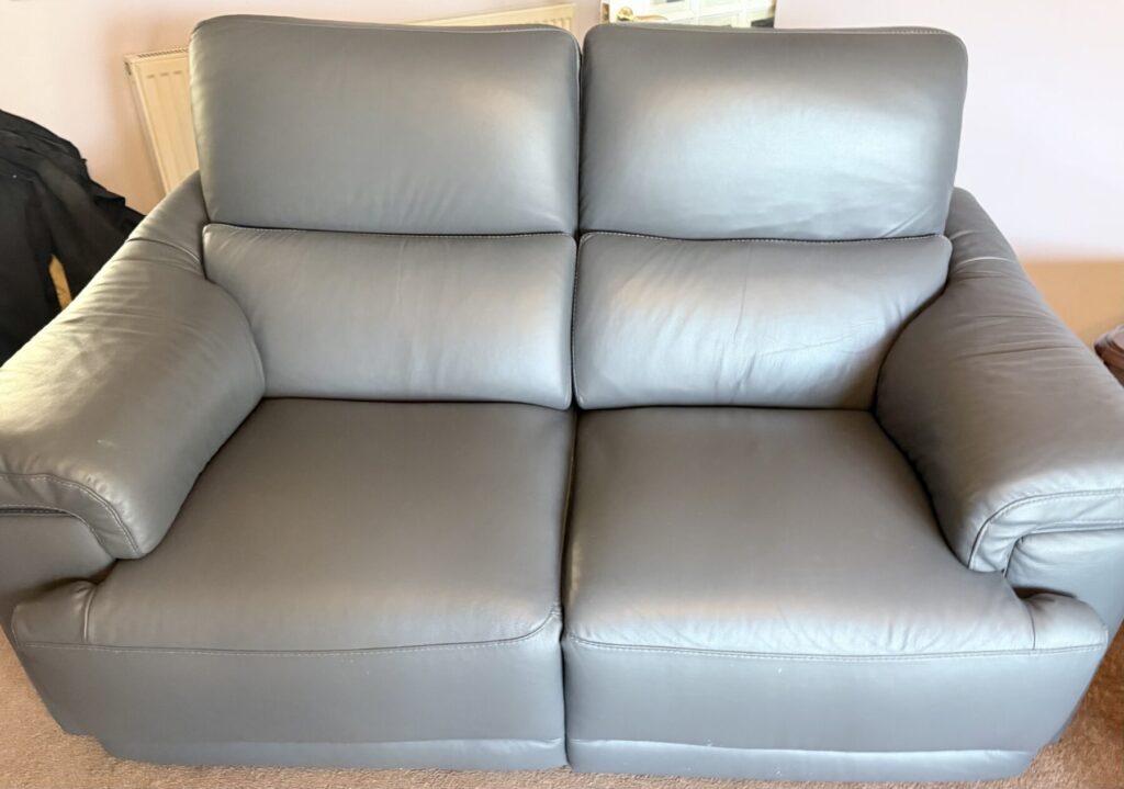Grey leather two-seater sofa professionally restored with repaired cushions and refreshed upholstery.
