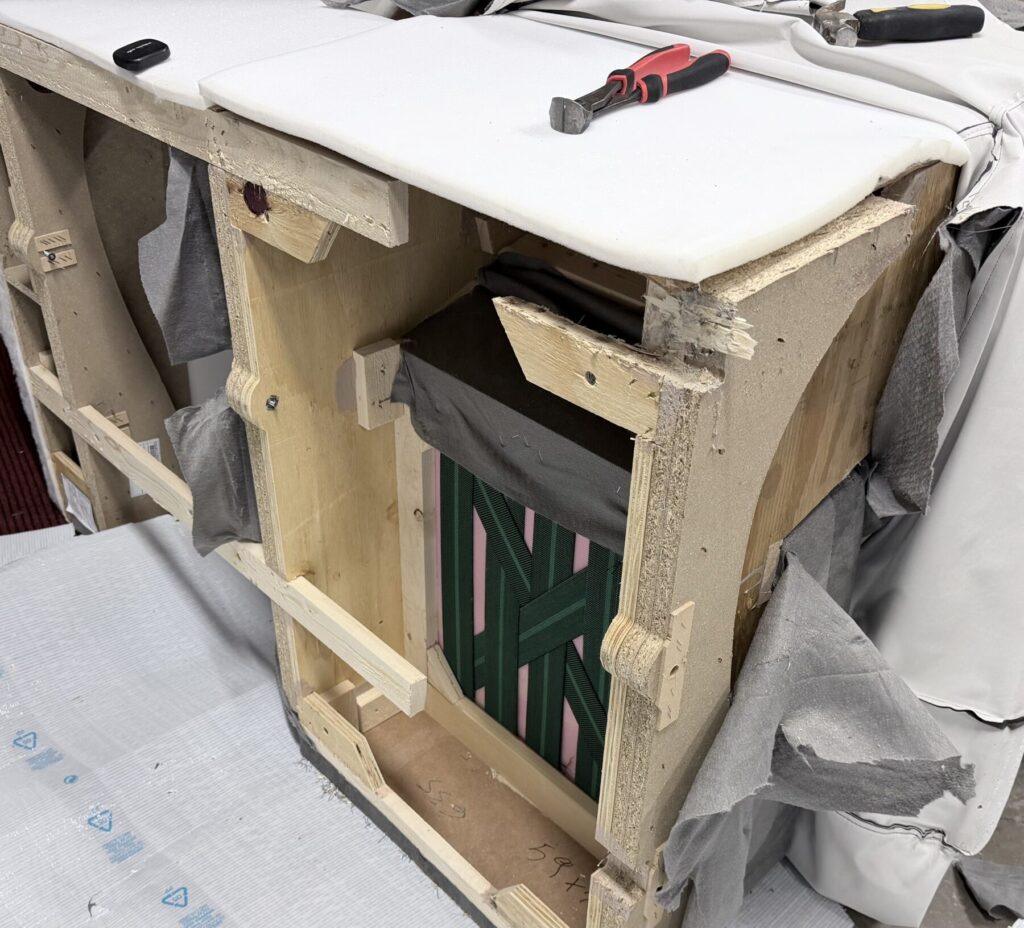 Exposed sofa frame showing structural damage being repaired as part of a professional furniture restoration service.