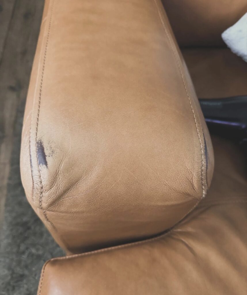 Brown leather chair armrest with worn leather surface requiring repair and colour restoration.