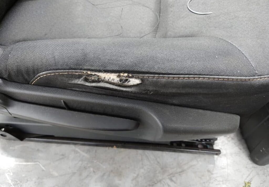 Vehicle seat with torn side bolster fabric prior to upholstery repair and restoration.