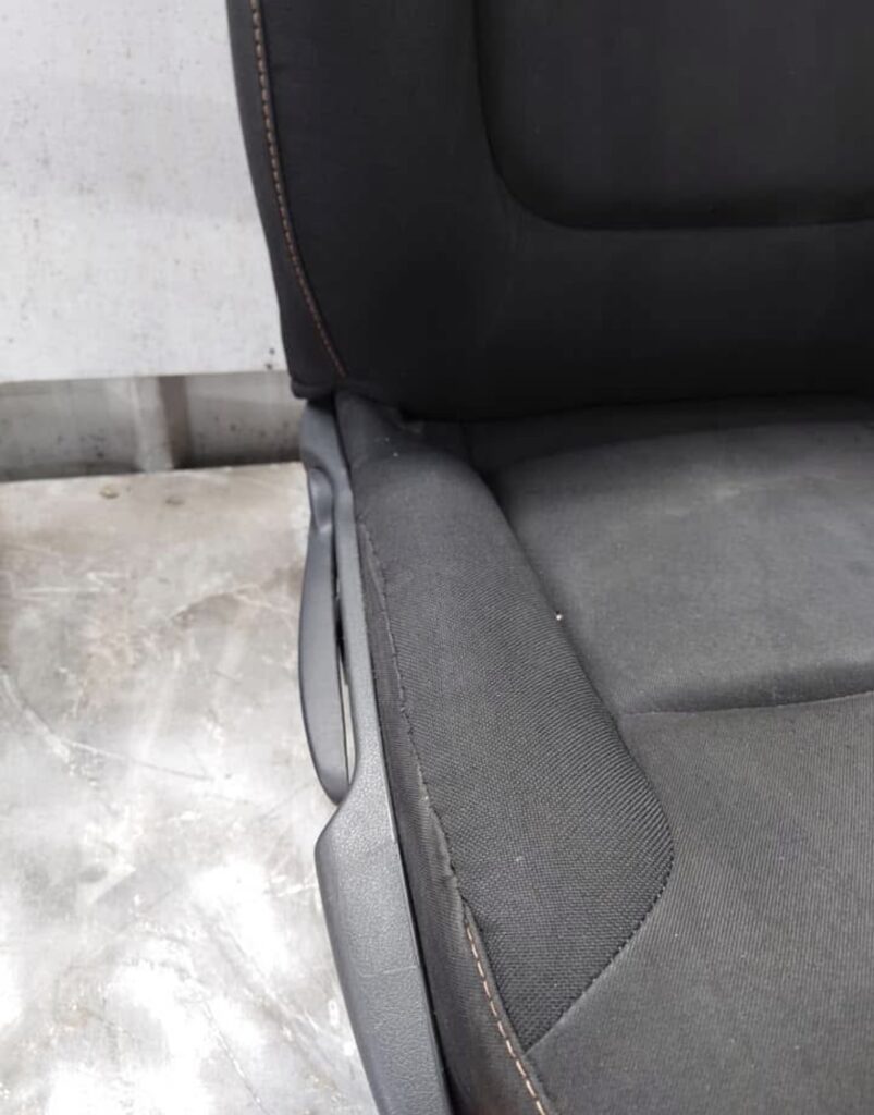 Close-up of a vehicle seat with damaged fabric trim requiring professional seat repair and upholstery restoration.