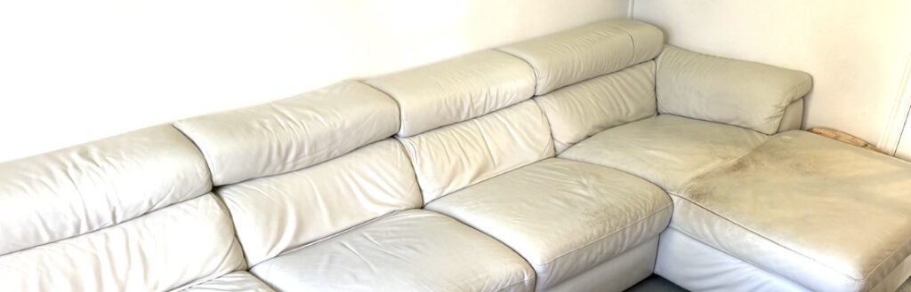 White leather corner sofa showing signs of wear and discolouration prior to repair and restoration.